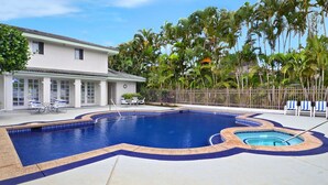 Una piscina dalla forma particolare, circondata da una recinzione, con sedie e un edificio sullo sfondo.