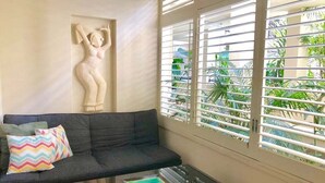 A living room with a sofa, a coffee table, a wall sculpture, and a window with blinds. - Beachside Family Retreat - Paradiso 111 (Tweed)