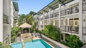 A hotel with a swimming pool, outdoor seating, and lush greenery. - Beachside Family Retreat - Paradiso 111 (Tweed)