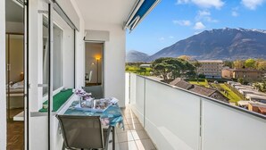 A balcony with a table, chairs, and a view of mountains and buildings. - Il Tenero Appartamento With Balcony and Parking (Tenero-Contra)
