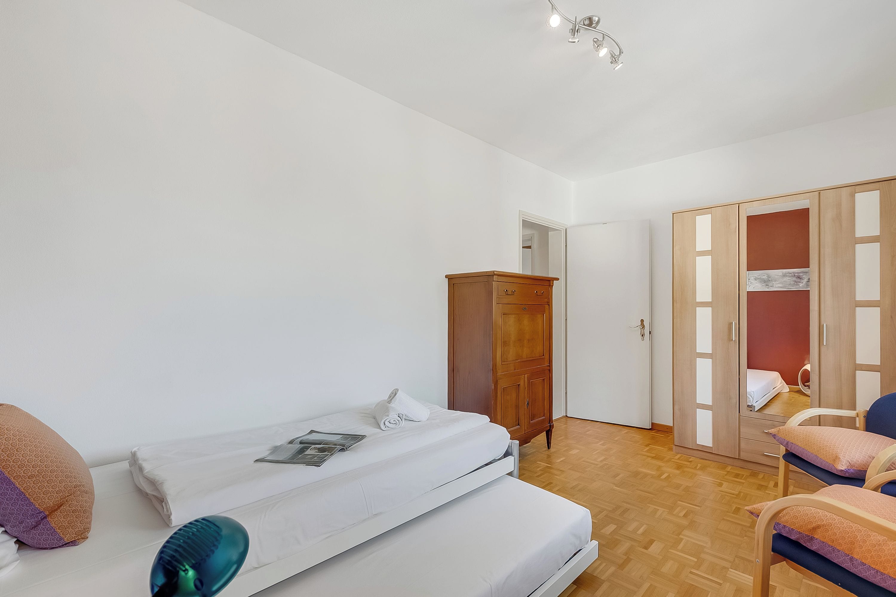 A bedroom with a bed, wardrobe, and a chair.