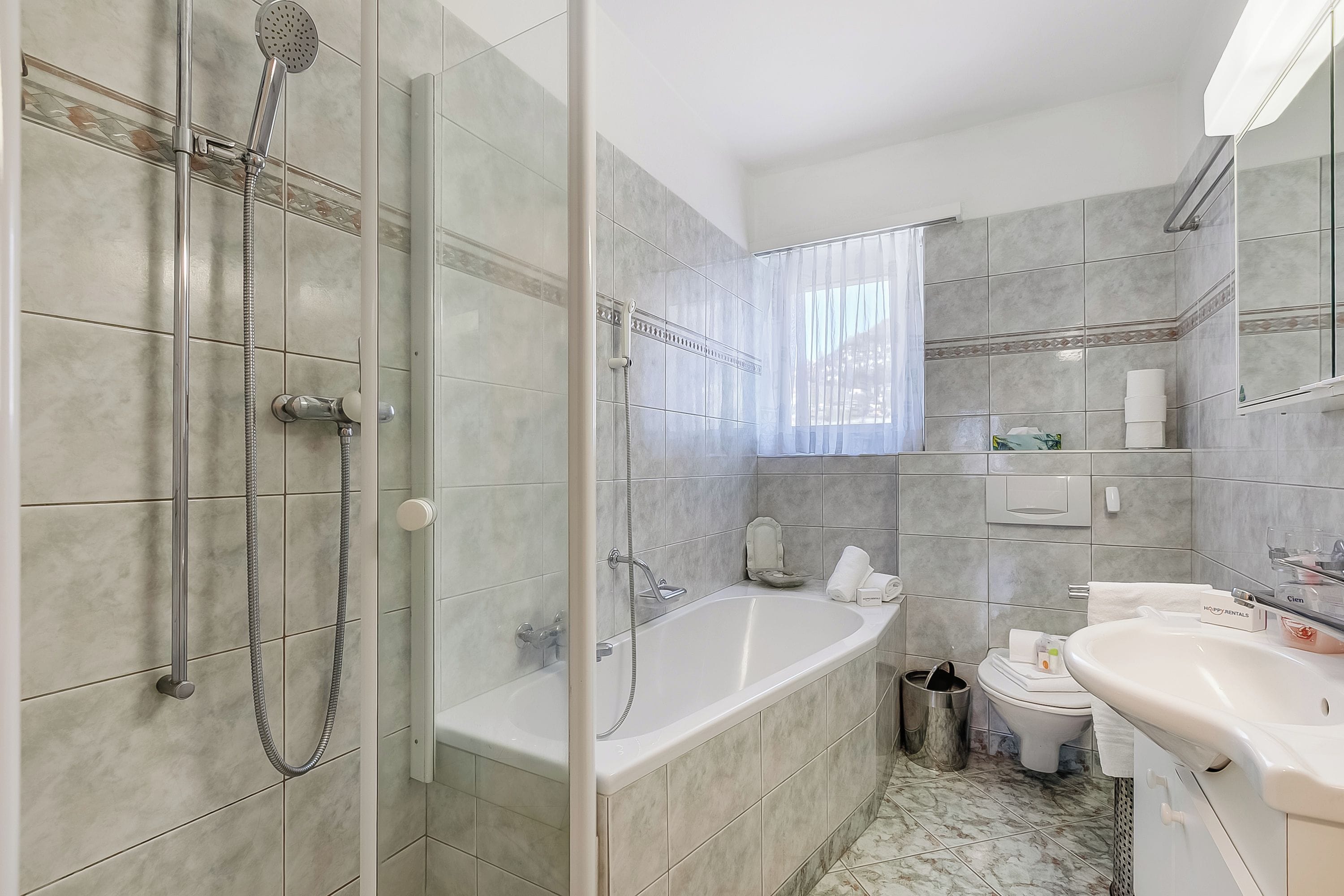 Un baño con ducha de vidrio, bañera, inodoro y lavamanos.