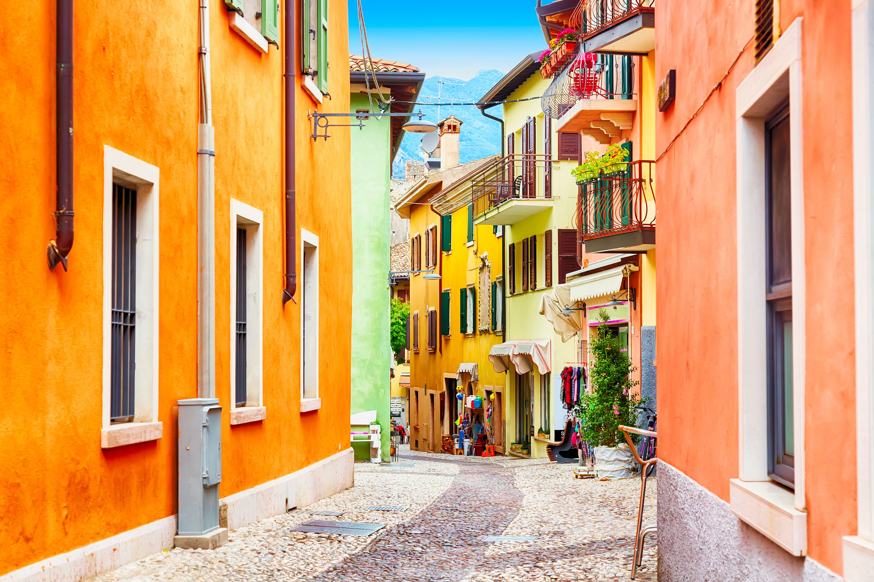 A narrow street with colorful buildings, a cobblestone path, and a mountain in the background.