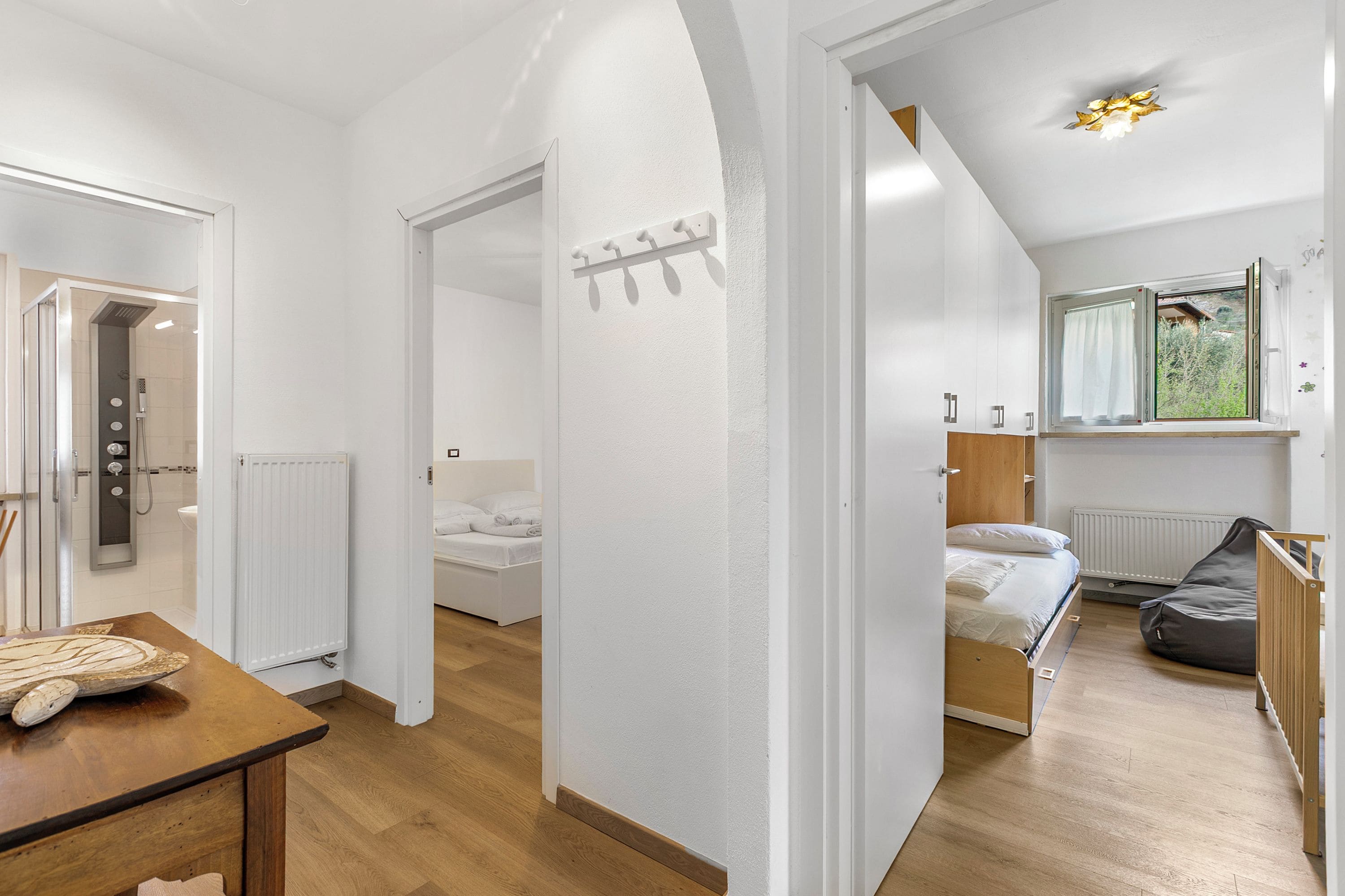 A modern bedroom with a bed, a window with curtains, a radiator, and a wooden table.