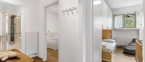 Un dormitorio moderno con cama, una ventana con cortinas, un radiador y una mesa de madera.