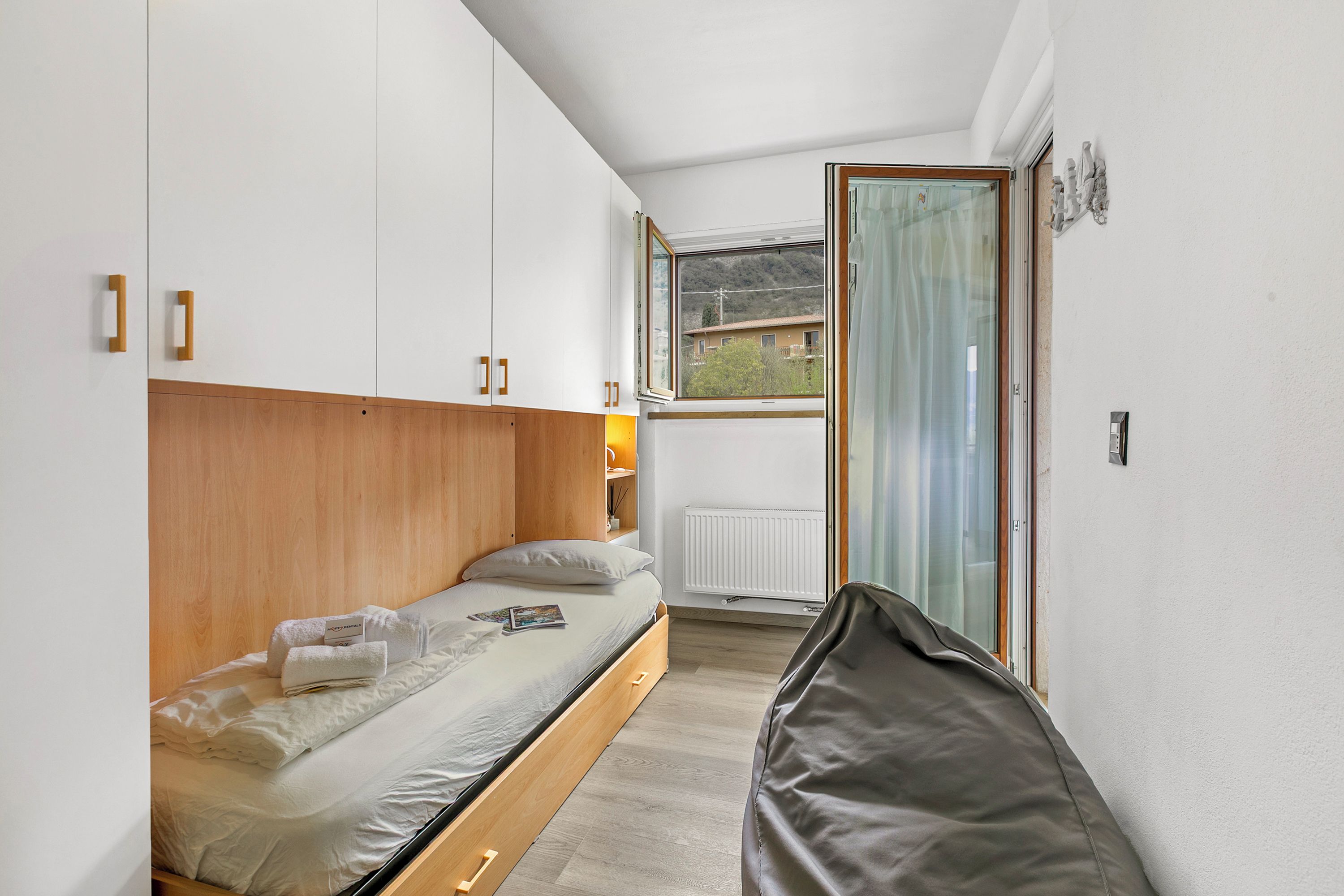 Ein Schlafzimmer mit einem Bett, Holz-Kopfteil, einem Fenster mit Aussicht und einer Heizung.