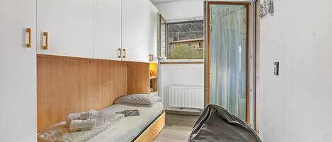 Ein Schlafzimmer mit einem Bett, Holz-Kopfteil, einem Fenster mit Aussicht und einer Heizung.