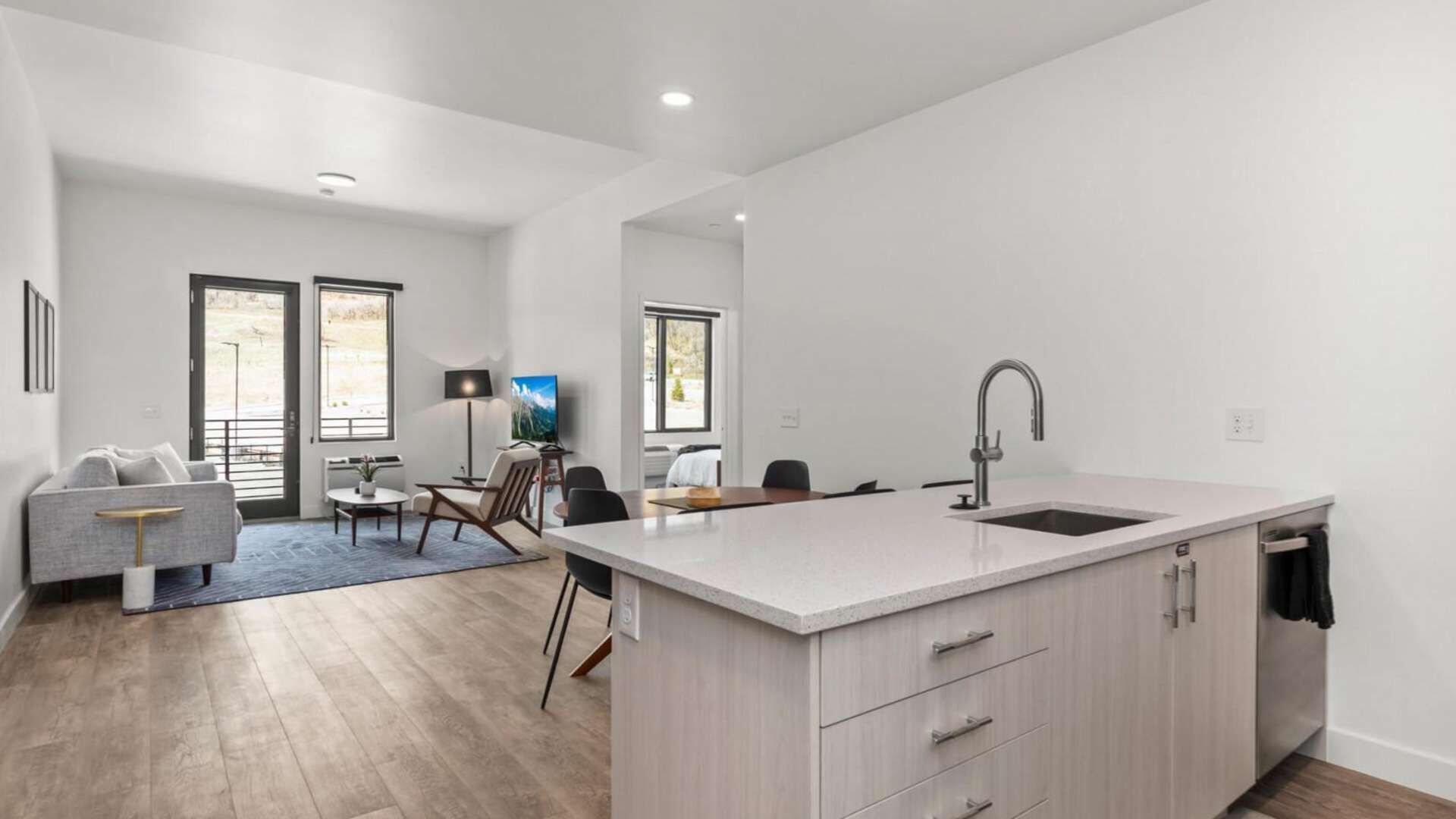A modern apartment with a kitchen, dining area, and living room.