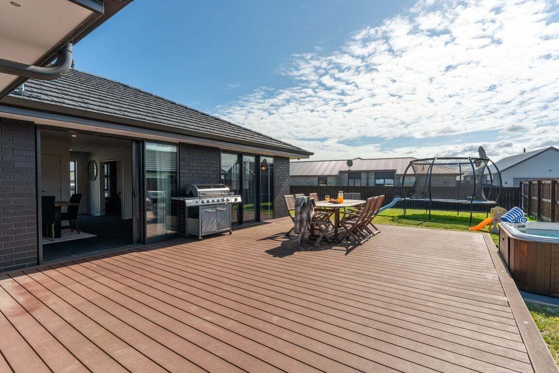 Una terraza moderna al aire libre con una parrilla, una mesa de comedor y un jacuzzi.