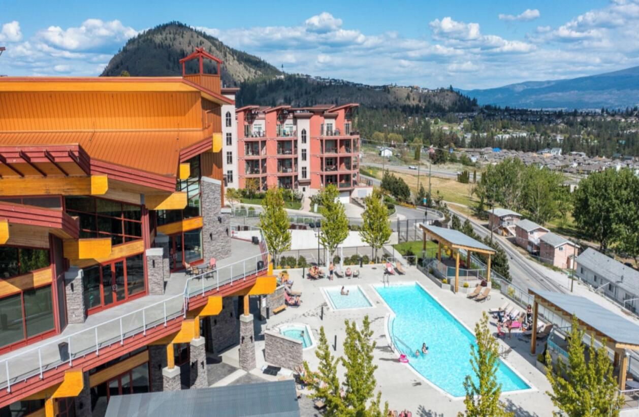 A hotel with a pool area, multiple balconies, and a view of the surrounding landscape.