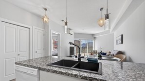Eine moderne Küche mit Granit-Arbeitsplatten, einer doppelten Spüle und Pendelleuchten.