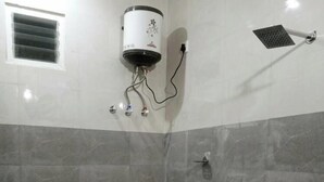 A bathroom with a toilet, a shower, and a water heater. - Malabar Cottage - Panoramic Mountain View (Kodaikanal)