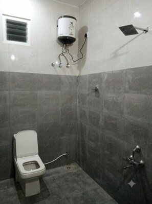 A bathroom with a toilet, a shower, and a water heater. - Malabar Cottage - Panoramic Mountain View (Kodaikanal)