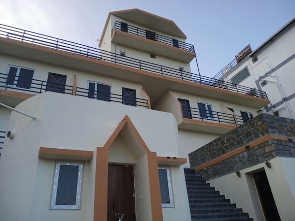 Un immeuble à plusieurs étages, doté de balcons, d’une entrée principale et d’un escalier menant à un niveau supérieur.