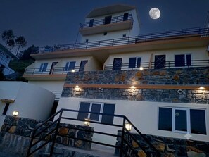 Un edificio de varios pisos con detalles de piedra, un balcón y una escalera que conduce a la entrada.