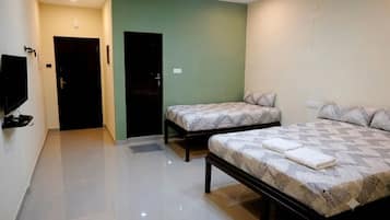 A hotel room with two beds, a television, and a door.