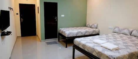 Una habitación de hotel con dos camas, un televisor y una puerta.