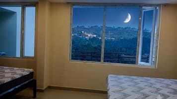 A bedroom with a large window, a bed, and a view of a hillside.
