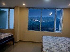 A bedroom with a large window, a bed, and a view of a hillside. - Malabar Cottage - Panoramic Mountain View (Kodaikanal)
