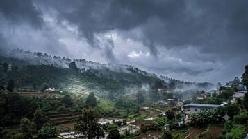 A rural landscape with terraced fields, a small settlement, and a mountain range in the background.