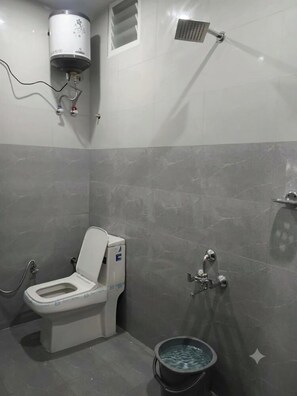 A bathroom with a toilet, a shower, and a water heater. - Malabar Cottage - Panoramic Mountain View (Kodaikanal)