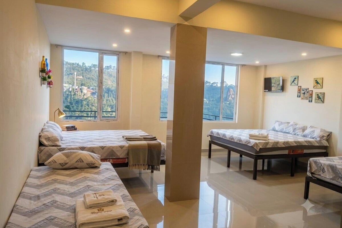 Habitación de hotel con dos camas, un ventanal grande y vistas al exterior.