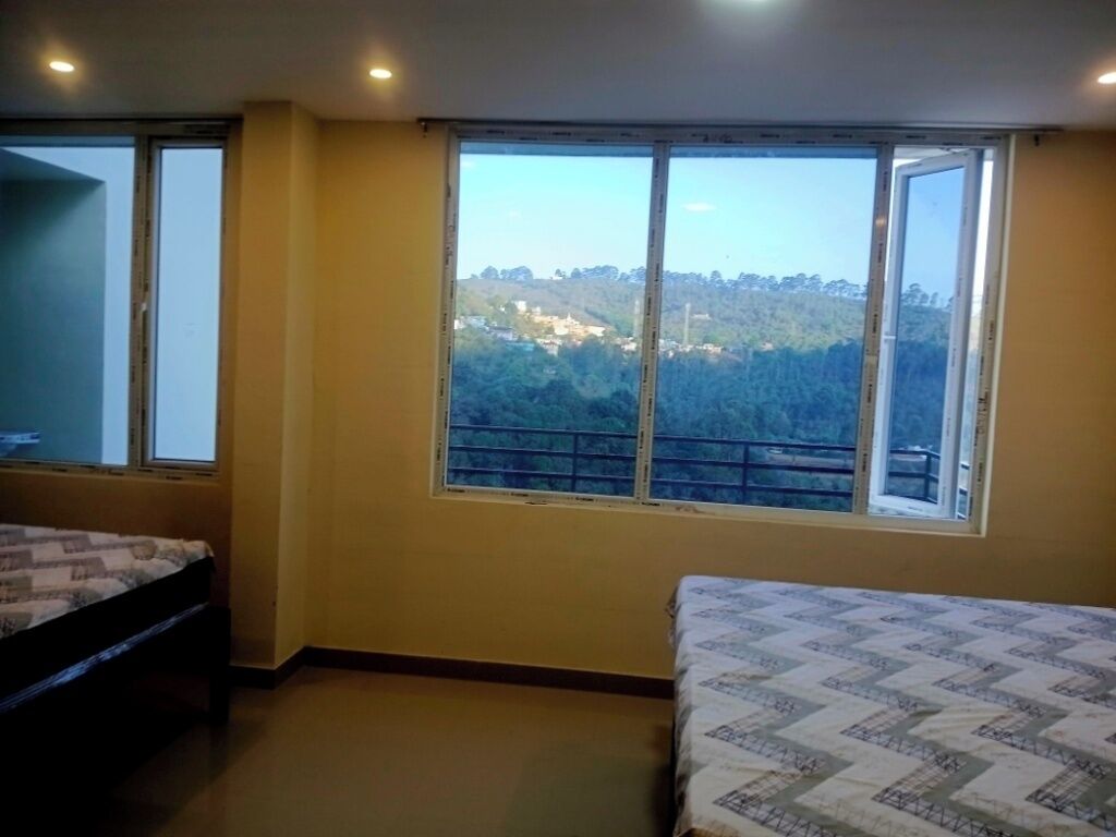 Una habitación con cama, ventana y vistas a un paisaje montañoso, e iluminación empotrada en el techo.