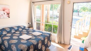 Une chambre à coucher avec un lit, une fenêtre et une porte donnant sur l’extérieur.