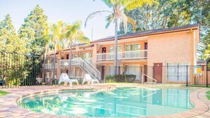 Un motel à deux étages doté d’une piscine, d’un espace extérieur aménagé et d’une terrasse clôturée.