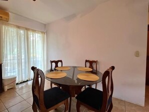 A dining area with a round table and four chairs, each with a cushion. - 🏡✨ Comfort and style at Marine Sunset #7 (2BR/2BA - Ground Floor) (Playas del Coco)