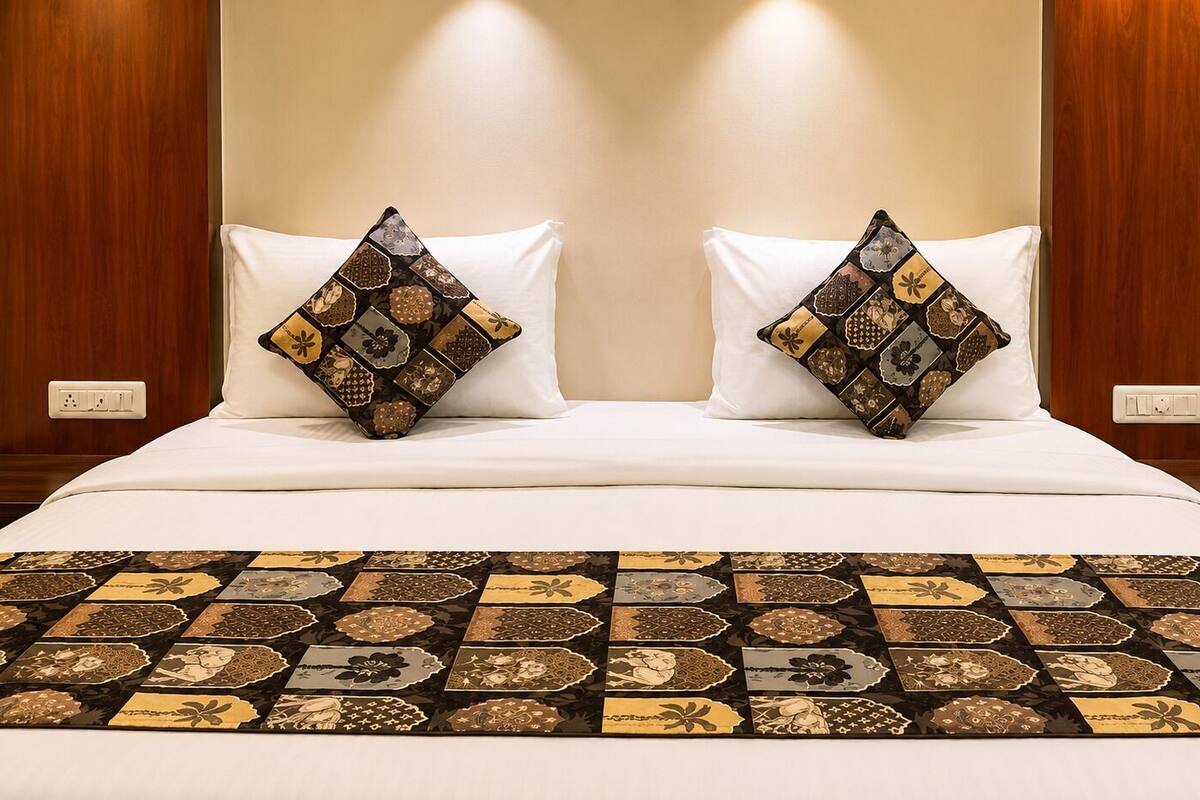 Una cama bien hecha con almohadas estampadas y una colcha decorativa.