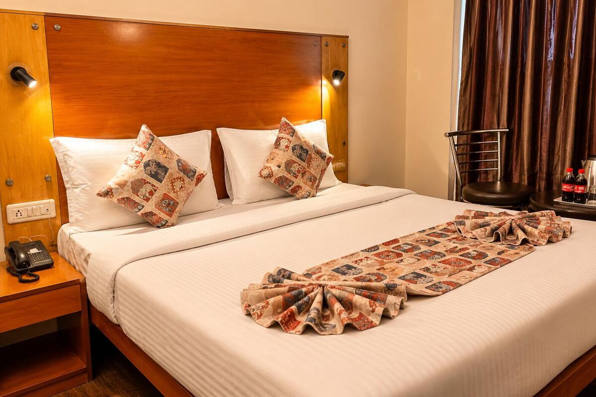 Una cama bien hecha con almohadas estampadas, un teléfono en la mesita de noche y un plaid decorativo.