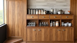 Un armario de madera para cocina con varios cajones y estantes, que contiene utensilios y vajilla.