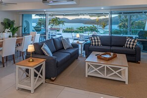 A modern living room with two sofas, a coffee table, and a dining area with chairs and a table. - Bella Vista East 2 (Hamilton Island)