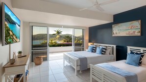 Une chambre avec deux lits, une télévision, un bureau et une vue sur la plage et les montagnes.