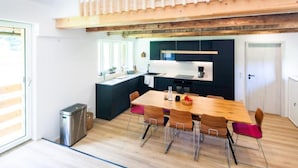 Una cocina moderna con una mesa y sillas de madera, una pequeña isla y un horno empotrado.