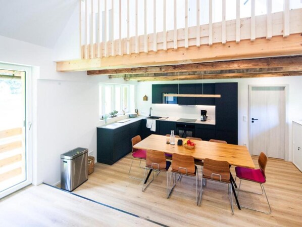 Una cocina moderna con una mesa y sillas de madera, una pequeña isla y un horno empotrado.