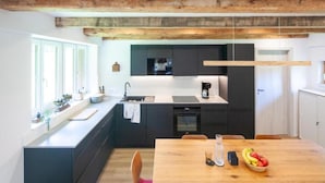 Una cocina moderna con una isla de madera, un comedor con mesa de madera y vistas al exterior.