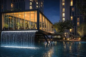 A modern hotel with a glass facade, a waterfall feature, and a pool. - The Shore Residence Melaka (Malacca City)