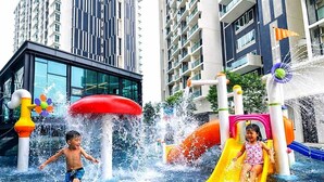 Área de recreação com água, incluindo tobogãs e jatos, cercada por edifícios modernos.