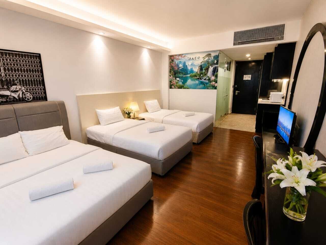 A hotel room with three beds, a television, a mirror, and a painting on the wall.