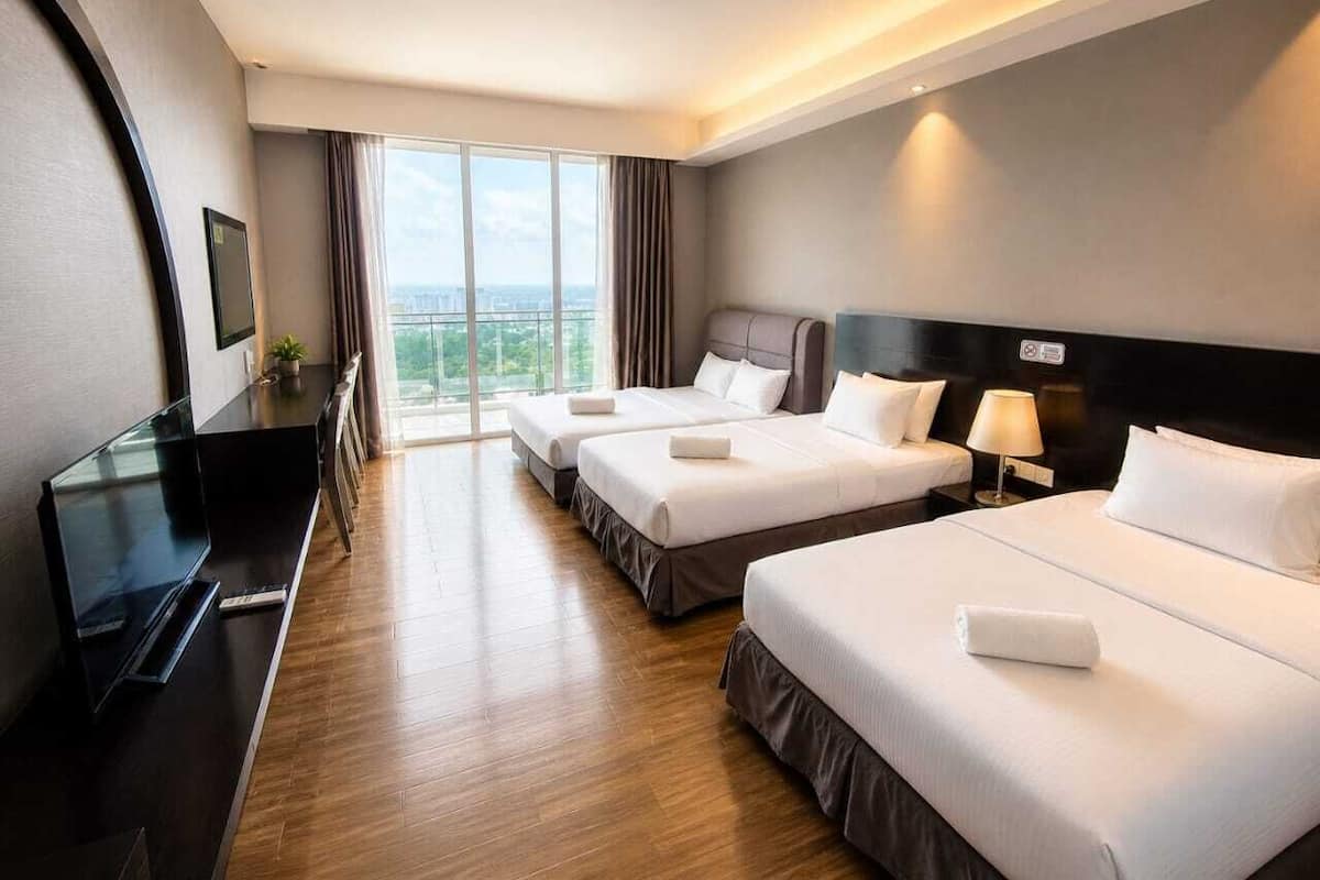 Ein Hotelzimmer mit zwei Betten, einem Fernseher, einem Schreibtisch und Blick auf die Stadt.