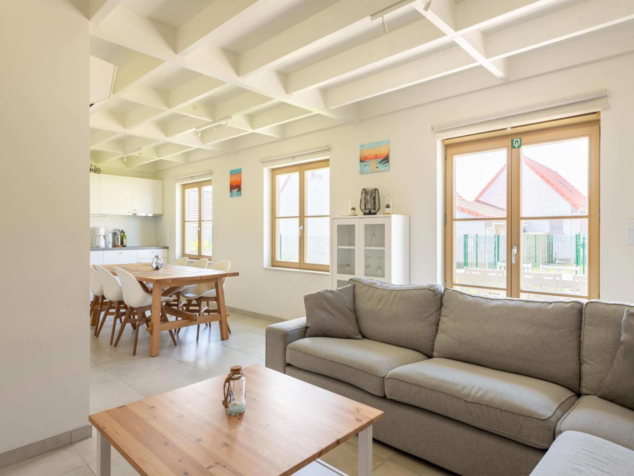 A modern living room with a sofa, a wooden table, and a dining area with chairs.