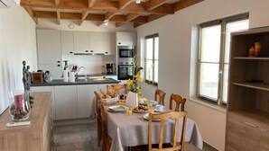 Een moderne keuken met houten balken, een eettafel gedekt voor vier personen en een ontbijtbuffet.