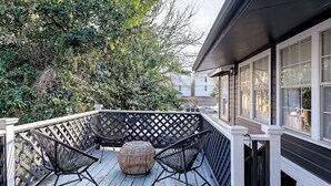 Una terraza de madera con dos sillas y una mesa redonda, rodeada por un cerramiento de celosía.