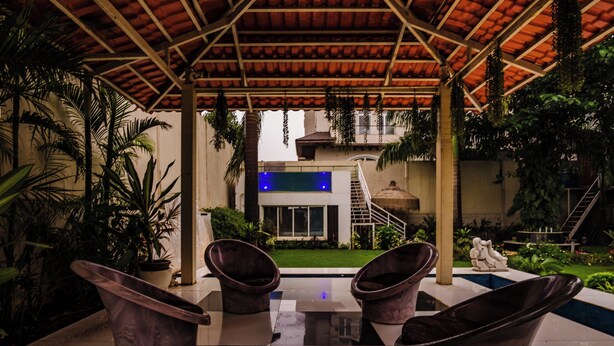 A covered outdoor area with a pool, two chairs, and a staircase leading to a building. - Moonstone Meadows Suite By Alaya Stays (Mawal)