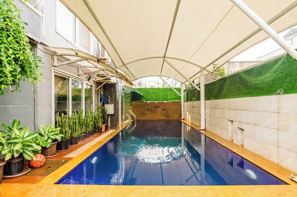 An indoor swimming pool with a covered area, potted plants, and a basketball on the side. - Moonstone Meadows Suite By Alaya Stays (Mawal)
