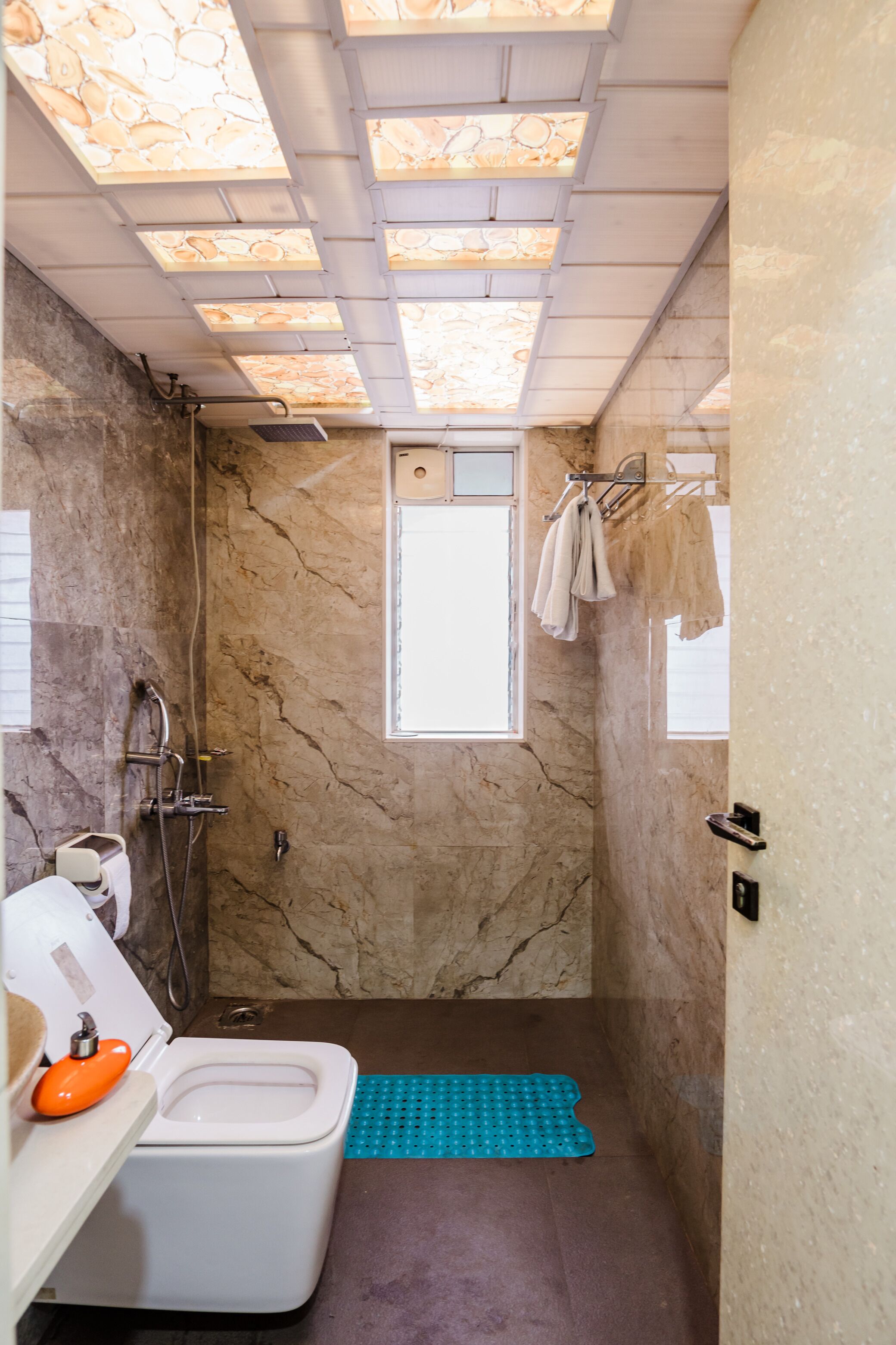 A bathroom with a toilet, shower, and a window.