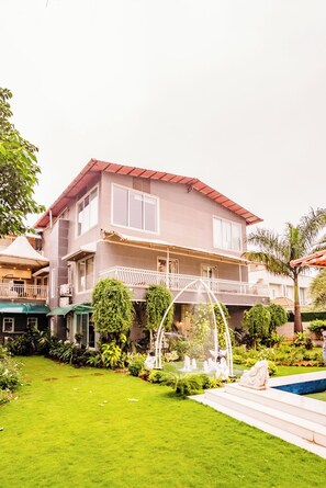 A two-story house with a balcony, a swimming pool, and a garden with a fountain. - Moonstone Meadows Suite By Alaya Stays (Mawal)