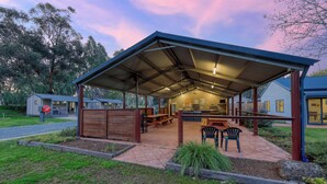 A covered outdoor dining area with picnic tables, a barbecue grill, and a kitchen area. - Deniliquin Riverside Caravan Park (Deniliquin)